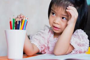 la ragazza era seduta e ascoltava gli adulti che le insegnavano i compiti e giocava il colore del legno nel vetro bianco. i bambini erano perplessi dalle istruzioni. foto