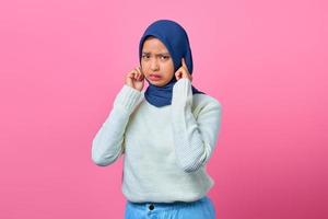 ritratto di una giovane donna asiatica arrabbiata che si copre le orecchie con un dito foto