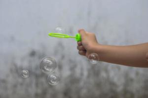una ragazza che tiene in mano un creatore di bolle e le fa esplodere. foto