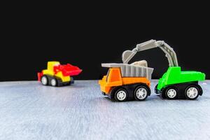costruzione opera concetto di giocattolo modello camion terna trattore su il strada e sfondo foto