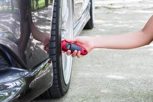 mano donne uso pneumatico valutare dai un'occhiata aria pressione di auto su il calcestruzzo strada primo concetto di guidare foto