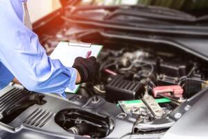 tecnico dai un'occhiata elenco problema di auto nel bianca carta con motore camera servizio concetto nel laboratorio foto