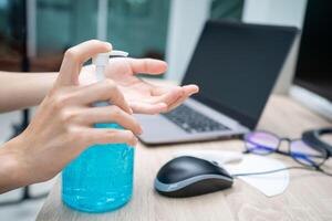 donne uso alcool gel per protezione e pulizia un' mano dopo uso computer, funzionante a casa concetto foto