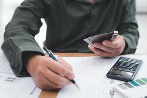 ingegnere tecnico hold tastatore valutare per design opera e uso matita Scrivi su disegno nel ingegneria opera con calcolatrice matita e disegno su tavolo foto