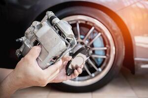 un' uomo Tenere standard calibro e freno tampone scorta parte nel aggiornare servizio Manutenzione azione concetto freno sistema di auto foto