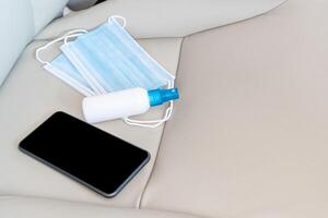 alcool spray maschera e smartphone siamo posto su il auto posto a sedere di base antivirus protezione attrezzatura nel auto uso ogni giorno foto