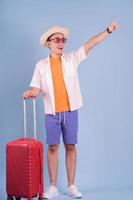 giovane uomo asiatico che tiene la valigia rossa su sfondo blu
