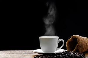 bianca caffè boccale e caffè fagiolo su il legna tavolo nel buio sfondo foto