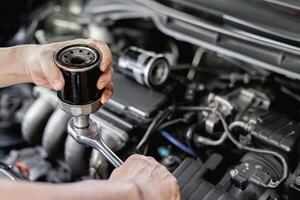 vicino su mano un' uomo prendere via vecchio olio filtro a partire dal chiave inglese nel mano uomo vecchio filtro modificare nel motore camera servizio concetto di auto foto