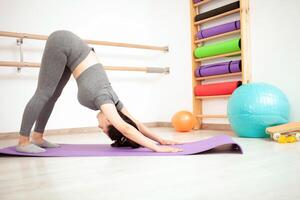 donna fa ponte, ginnasta nel palestra. palle nel sfondo foto