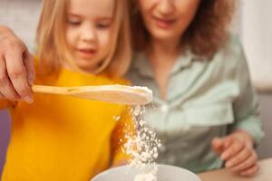 nonna e nipotina siamo fabbricazione torta nel cucina, contento famiglia, donna e bambino siamo sorridente. versare Farina. foto