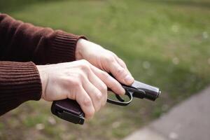 un' uomo addebiti un' pistola contro un' verde erba. armi da fuoco pistola all'aperto. sport, Hobby foto