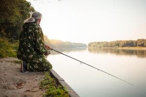 anziano concetto. pensionato Pesci su il fiume nel il suo scorta volta. un' utile passatempo, all'aperto attività nel vecchio età. copia spazio. alba foto