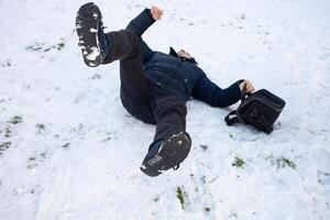 un' uomo cascate nel il neve. il uomo scivolato e era ferito. caduta su Ghiaccio. inverno. frattura, ammaccare, dislocazione. foto