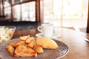 colazione, cena, pranzo nel un' ristorante, bar. al forno patate con Polpette, Cesare insalata, caffè Americano. intervistatore, delizioso cibo, grande finestre, naturale luce del sole. sfocato sfondo foto