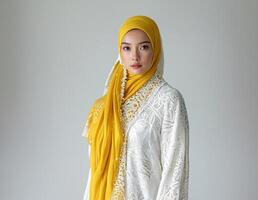 ai generato asiatico modello nel bianca kebaya e giallo hijab foto
