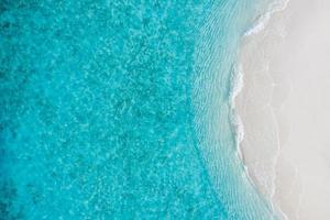 estate mare belle onde, acqua di mare blu in una giornata di sole. vista dall'alto dal drone. vista aerea del mare, incredibile sfondo di natura tropicale. bellissimo mare luminoso con spruzzi di onde e concetto di spiaggia di sabbia foto