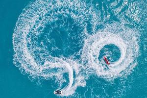 le persone stanno giocando a una moto d'acqua in mare. vista aerea. vista dall'alto. incredibile sfondo della natura. sport all'aria aperta di fresca libertà. giornata di avventura. divertimento acquatico oceano turchese chiaro sulla spiaggia tropicale foto