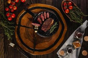 fette alla griglia berretto scamone bistecca con ramo di rosmarino, forchette dorate e spezie su tagliere di legno - picanha brasiliana - vista dall'alto. foto