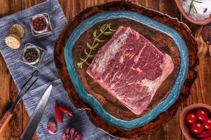 chorizo argentino di lonza di manzo crudo su un tagliere di legno resinato con spezie - vista dall'alto. foto