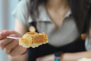 giovane donna che mangia croissant in un bar foto