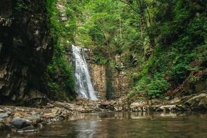 cascata con lago tra rocce e bosco foto