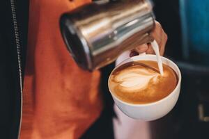 barista scrosciante latte su caffè tazza fabbricazione cuore foto