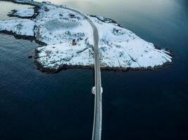 aereo Visualizza di strada ponte al di sopra di nevoso isola con scandinavo Casa su inverno nel arcipelago a lofoten isole foto