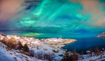 aurora Borealis raggiante al di sopra di scandinavo villaggio su costa nel inverno a lofoten isole foto