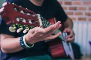 un' giovane uomo è praticante giocando chitarra nel un' musica pratica camera prima l'esecuzione nel ordine per ridurre il sbaglio di giocando chitarra su palcoscenico. vicino su giovane uomo è Tenere chitarra accordi per la pratica. foto