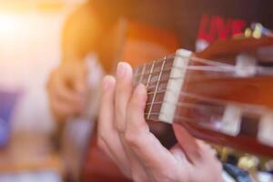 un' giovane uomo è praticante giocando chitarra nel un' musica pratica camera prima l'esecuzione nel ordine per ridurre il sbaglio di giocando chitarra su palcoscenico. vicino su giovane uomo è Tenere chitarra accordi per la pratica. foto