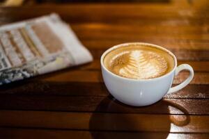 caldo latte macchiato caffè tazza con giornale su legna tavolo foto