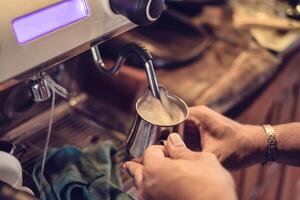 mano barista vapore latte nel metallo boccale su caffè creatore foto