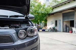 davanti auto con faro e Aperto motore controllo nel box auto foto