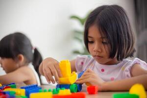 adorabile bambina che gioca a blocchi giocattolo in una stanza luminosa foto