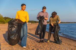 terra giorno. volontari attivisti squadra raccoglie spazzatura pulizia di spiaggia costiero zona. donna mans con spazzatura nel spazzatura Borsa su oceano costa. ambientale conservazione costiero zona pulizia foto