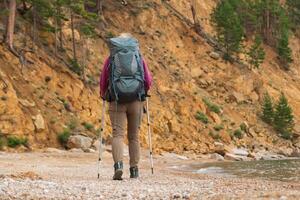 escursioni a piedi turismo avventura. irriconoscibile escursionista ragazza turista con zaino a piedi vicino lago. zaino in spalla donna godendo bellissimo spiaggia Visualizza. indietro Visualizza donna godere escursione il trekking turismo attivo vacanza foto