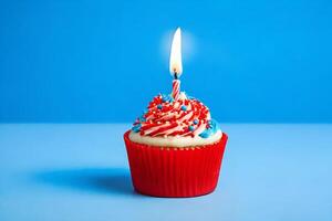 ai generato Cupcake con rosso spruzzatori e illuminato candela su blu sfondo. foto
