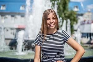 sorridenti giovane donna caucasica in abiti casual fuori in una giornata di sole vicino alla fontana foto