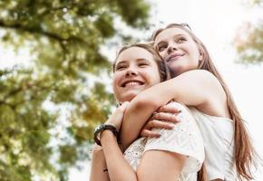 due migliori amici che si abbracciano fuori in una giornata estiva divertendosi foto