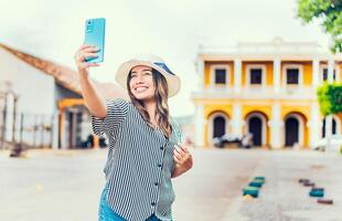 contento turista ragazza assunzione autoscatto nel il Cattedrale di granata. giovane viaggio donna con cappello assunzione un' autoscatto nel un' piazza foto