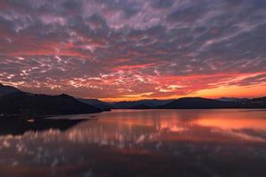il lago della sera rifletteva il bagliore del tramonto e le montagne foto