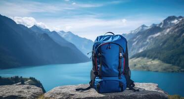 ai generato blu zaino su un' montagna con montagne e lago nel sfondo foto