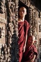 ritratto di un gruppo di monaci asiatici novizi in piedi davanti alla porta del tempio foto