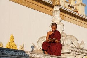 giovane monaco novizio asiatico che legge un libro al monastero foto