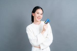 ritratto di una giovane donna asiatica adorabile in maglione che mostra la carta di credito con lo spazio della copia foto
