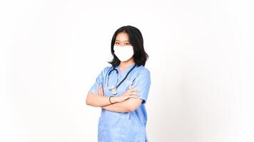 giovane asiatico femmina medico utilizzando medico maschera Tenere braccia e guardare a telecamera isolato su bianca sfondo foto