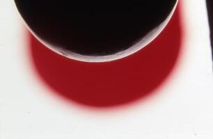 un' rosso liquido è visto nel il mezzo di un' bicchiere foto