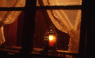 un' candela illuminato di un' lanterna nel un' finestra foto
