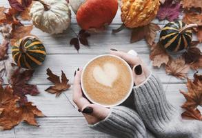 mani femminili che tengono una tazza di caffè caldo, posa piatta autunnale foto